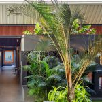 PROJECT INFORMATION Project Name: Experience Centre Location: Koyembedu, Chennai Site Area: 0.75 Acre Built-up Area: 0.20 Lac sft No of Floors: 1 Status: Completed Year of Completion:2021 Firm: CnT Architects Design Team (CnT): Amit Rastogi, Karthik P Nair, Anupama Rao Consultants: Metal Queen (Structure), Mukund Associates (Plumbing), Lite Lab (Lighting Design), Oikos (Landscape), Graphics Beyond (Graphic Design) Photography: Andre Fanthome INTRO (470 Words) Located in Chennai metropolitan at a close proximity to city’s transit hub, the site is approached from a highly buzzing Poonamalli high road. Three key components- A marketing office, an Experience centre and a Construction site office are the core of the facility. ‘‘Journey through the project reveals intricately detailed spatial sequences carefully crafted by the thoughtful blend of Architecture, Landscape and Interior design. Visual frames and experiences unfold in layers to keep the visitor captivated & intrigued throughout.’’ A landscaped plaza creating a tranquil arrival experience is first on the entry sequence; doubling up as the interface between city and the main program filtering the unwanted external buzz. At point of arrival, one gets a glimpse of Intricate roof canopy of marketing office hovering over plaza feature wall, creating a sense of mystery for what lies ahead. ‘Marketing office’ is accessed through a curved alley; meandering through lush green it guides visitors to an arrival court revealing full view of the architecture. The form; conceived as an expansive canopy floating over slender metal columns shelters many pods beneath to hold the programme. Pods contain air-conditioned spaces for the reception, gallery, media room, customer studios etc. Arranged in a free plan form, their placement defines a natural movement spine along the longitudinal axis. Intricate design of ceiling and series of skylights along the spine enriches the experience of moving through the space. The ‘Experience centre’ is accessed through a landscape buffer placed at the end of marketing office. Steps through the landscape graduate to a scaled down movement spine representing the proportions of an apartment lobby, leading to three model apartment prototypes put on display here. Placement of model apartments is juxtaposed with various semi open and open public spaces to create a very engaging and enthralling environment. Overall visitor journey is designed as two-way experience and design features are tactfully placed along the path and at important nodes to be discovered gradually and slowly. A discreetly placed entryway at the end of experience centre leads in to the ‘Construction site office’. Encouraged to see the importance given to design of spaces for the construction team; visitors are escorted right through the common area of site office arriving on to a viewing deck opening to a panoramic view of the under construction residential township which is rising up in the background. Environmental impact: Life span of facility is five years, post which it will be dismantled. Hence, majority of the structure is designed in steel for recyclability and reuse. The modular structural elements are going to be used for another project of the developer, making this project as sustainable as possible. Circulation spaces are well shaded and allow a lot of cross breezes, essential for comfort in hot humid weather of Chennai; reducing need of air conditioning to the minimum. - Sheet16