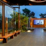 PROJECT INFORMATION Project Name: Experience Centre Location: Koyembedu, Chennai Site Area: 0.75 Acre Built-up Area: 0.20 Lac sft No of Floors: 1 Status: Completed Year of Completion:2021 Firm: CnT Architects Design Team (CnT): Amit Rastogi, Karthik P Nair, Anupama Rao Consultants: Metal Queen (Structure), Mukund Associates (Plumbing), Lite Lab (Lighting Design), Oikos (Landscape), Graphics Beyond (Graphic Design) Photography: Andre Fanthome INTRO (470 Words) Located in Chennai metropolitan at a close proximity to city’s transit hub, the site is approached from a highly buzzing Poonamalli high road. Three key components- A marketing office, an Experience centre and a Construction site office are the core of the facility. ‘‘Journey through the project reveals intricately detailed spatial sequences carefully crafted by the thoughtful blend of Architecture, Landscape and Interior design. Visual frames and experiences unfold in layers to keep the visitor captivated & intrigued throughout.’’ A landscaped plaza creating a tranquil arrival experience is first on the entry sequence; doubling up as the interface between city and the main program filtering the unwanted external buzz. At point of arrival, one gets a glimpse of Intricate roof canopy of marketing office hovering over plaza feature wall, creating a sense of mystery for what lies ahead. ‘Marketing office’ is accessed through a curved alley; meandering through lush green it guides visitors to an arrival court revealing full view of the architecture. The form; conceived as an expansive canopy floating over slender metal columns shelters many pods beneath to hold the programme. Pods contain air-conditioned spaces for the reception, gallery, media room, customer studios etc. Arranged in a free plan form, their placement defines a natural movement spine along the longitudinal axis. Intricate design of ceiling and series of skylights along the spine enriches the experience of moving through the space. The ‘Experience centre’ is accessed through a landscape buffer placed at the end of marketing office. Steps through the landscape graduate to a scaled down movement spine representing the proportions of an apartment lobby, leading to three model apartment prototypes put on display here. Placement of model apartments is juxtaposed with various semi open and open public spaces to create a very engaging and enthralling environment. Overall visitor journey is designed as two-way experience and design features are tactfully placed along the path and at important nodes to be discovered gradually and slowly. A discreetly placed entryway at the end of experience centre leads in to the ‘Construction site office’. Encouraged to see the importance given to design of spaces for the construction team; visitors are escorted right through the common area of site office arriving on to a viewing deck opening to a panoramic view of the under construction residential township which is rising up in the background. Environmental impact: Life span of facility is five years, post which it will be dismantled. Hence, majority of the structure is designed in steel for recyclability and reuse. The modular structural elements are going to be used for another project of the developer, making this project as sustainable as possible. Circulation spaces are well shaded and allow a lot of cross breezes, essential for comfort in hot humid weather of Chennai; reducing need of air conditioning to the minimum. - Sheet5