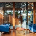 PROJECT INFORMATION Project Name: Experience Centre Location: Koyembedu, Chennai Site Area: 0.75 Acre Built-up Area: 0.20 Lac sft No of Floors: 1 Status: Completed Year of Completion:2021 Firm: CnT Architects Design Team (CnT): Amit Rastogi, Karthik P Nair, Anupama Rao Consultants: Metal Queen (Structure), Mukund Associates (Plumbing), Lite Lab (Lighting Design), Oikos (Landscape), Graphics Beyond (Graphic Design) Photography: Andre Fanthome INTRO (470 Words) Located in Chennai metropolitan at a close proximity to city’s transit hub, the site is approached from a highly buzzing Poonamalli high road. Three key components- A marketing office, an Experience centre and a Construction site office are the core of the facility. ‘‘Journey through the project reveals intricately detailed spatial sequences carefully crafted by the thoughtful blend of Architecture, Landscape and Interior design. Visual frames and experiences unfold in layers to keep the visitor captivated & intrigued throughout.’’ A landscaped plaza creating a tranquil arrival experience is first on the entry sequence; doubling up as the interface between city and the main program filtering the unwanted external buzz. At point of arrival, one gets a glimpse of Intricate roof canopy of marketing office hovering over plaza feature wall, creating a sense of mystery for what lies ahead. ‘Marketing office’ is accessed through a curved alley; meandering through lush green it guides visitors to an arrival court revealing full view of the architecture. The form; conceived as an expansive canopy floating over slender metal columns shelters many pods beneath to hold the programme. Pods contain air-conditioned spaces for the reception, gallery, media room, customer studios etc. Arranged in a free plan form, their placement defines a natural movement spine along the longitudinal axis. Intricate design of ceiling and series of skylights along the spine enriches the experience of moving through the space. The ‘Experience centre’ is accessed through a landscape buffer placed at the end of marketing office. Steps through the landscape graduate to a scaled down movement spine representing the proportions of an apartment lobby, leading to three model apartment prototypes put on display here. Placement of model apartments is juxtaposed with various semi open and open public spaces to create a very engaging and enthralling environment. Overall visitor journey is designed as two-way experience and design features are tactfully placed along the path and at important nodes to be discovered gradually and slowly. A discreetly placed entryway at the end of experience centre leads in to the ‘Construction site office’. Encouraged to see the importance given to design of spaces for the construction team; visitors are escorted right through the common area of site office arriving on to a viewing deck opening to a panoramic view of the under construction residential township which is rising up in the background. Environmental impact: Life span of facility is five years, post which it will be dismantled. Hence, majority of the structure is designed in steel for recyclability and reuse. The modular structural elements are going to be used for another project of the developer, making this project as sustainable as possible. Circulation spaces are well shaded and allow a lot of cross breezes, essential for comfort in hot humid weather of Chennai; reducing need of air conditioning to the minimum. - Sheet9