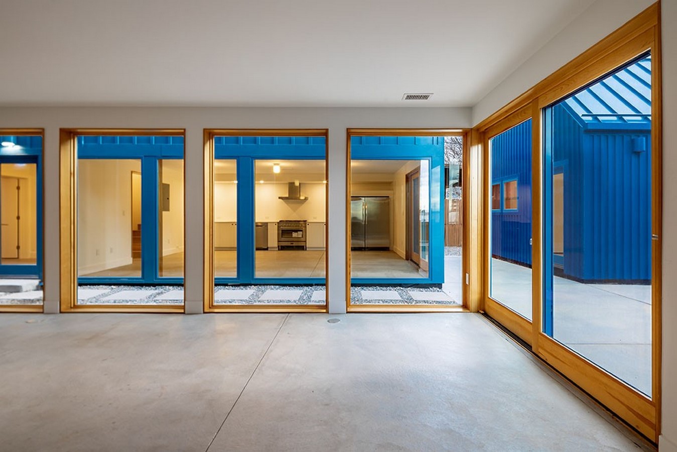 The view shows a glazed façade, folding wooden doors and windows to encourage social interaction_©PRODUCTORA